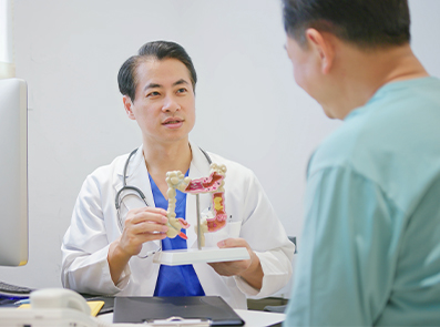 Arzt im Gespräch mit Patienten – zeigt ein Modell des Verdauungstraktes